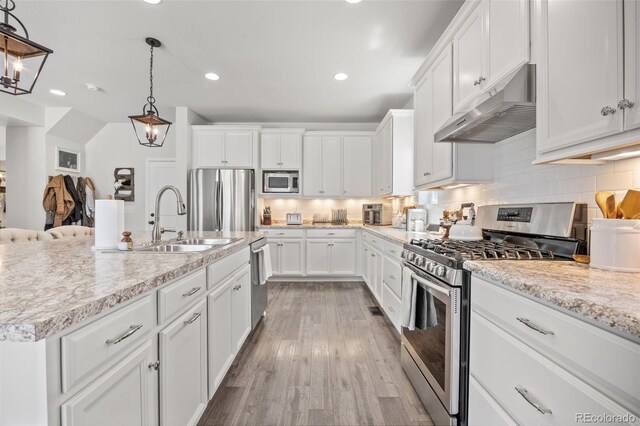 3535 Raintree Ln, Dacono, CO 80514 - kitchen featuring appliances with stainless steel finishes, under cabinet range hood, light wood finished floors, white cabinets, and recessed lighting