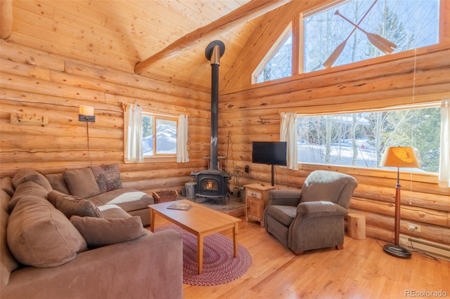 living area with beam ceiling, light wood-style flooring, a wood stove, high vaulted ceiling, and wooden ceiling