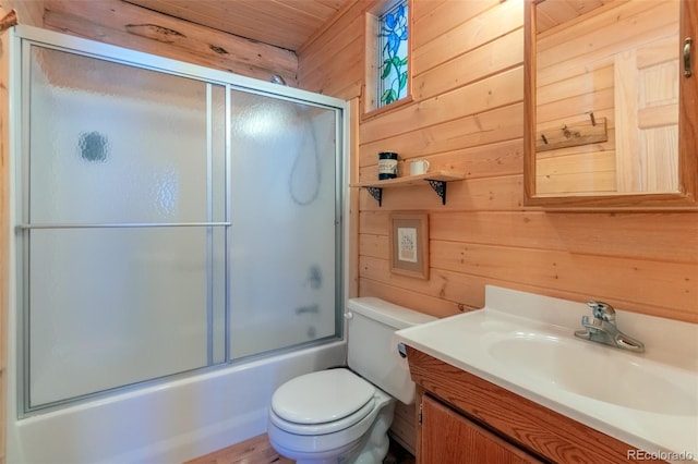 bathroom featuring enclosed tub / shower combo, wood walls, vanity, and toilet