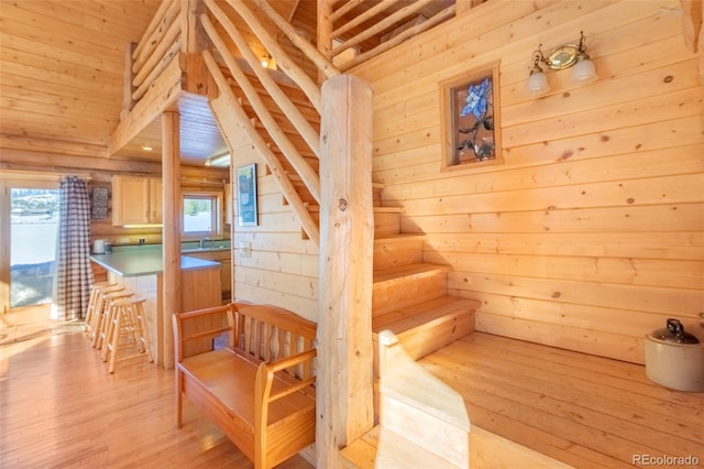 staircase with wood finished floors and wooden walls