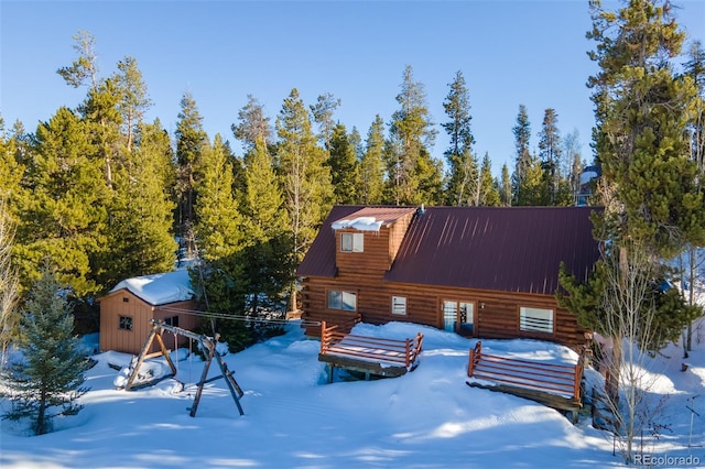 view of front of home with metal roof, an outdoor structure, and log siding