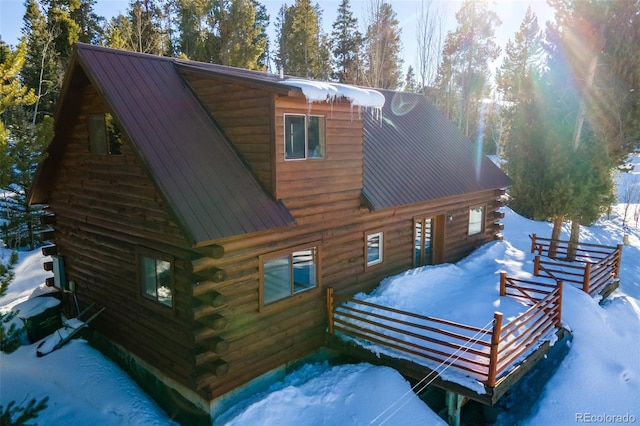 snow covered rear of property featuring metal roof and log exterior