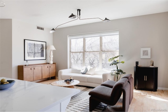 living area with light wood-type flooring, baseboards, and visible vents