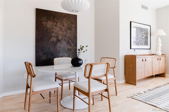 dining area featuring light wood-type flooring, visible vents, and baseboards