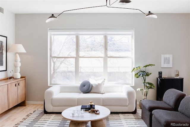 living area with light wood-style floors, baseboards, and visible vents