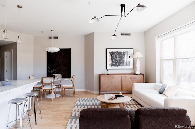 living room featuring light wood-style floors, baseboards, and visible vents