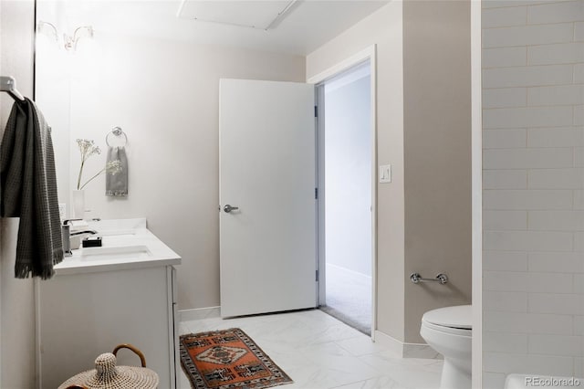 full bath featuring marble finish floor, double vanity, toilet, a sink, and baseboards