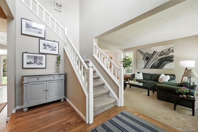 staircase featuring baseboards, a healthy amount of sunlight, and wood finished floors