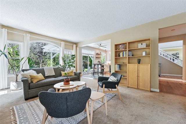 living area with light colored carpet, a textured ceiling, and a healthy amount of sunlight