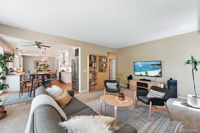 living area featuring baseboards, ceiling fan, and light colored carpet