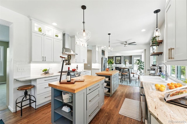kitchen featuring wood counters, wall chimney range hood, open shelves, and stainless steel fridge with ice dispenser