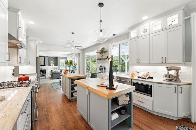 kitchen with stainless steel appliances, butcher block counters, open shelves, and a kitchen island