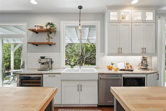 bar featuring a sink, pendant lighting, plenty of natural light, dishwasher, and wine cooler