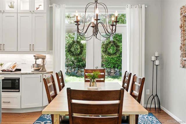 dining room with light wood-style floors, baseboards, and a notable chandelier
