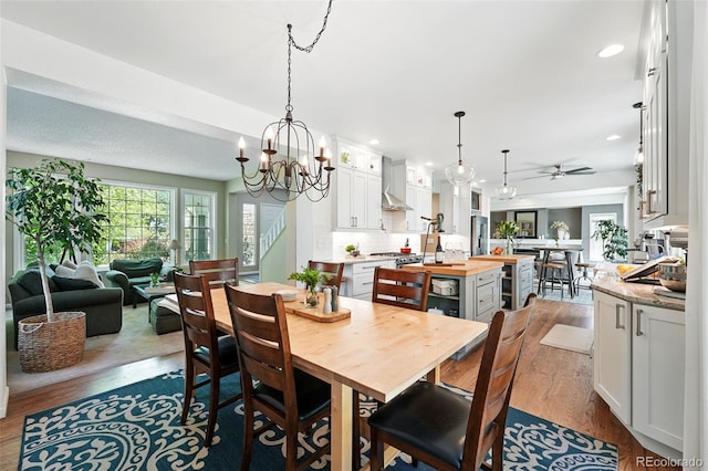 dining space featuring stairway, dark wood finished floors, recessed lighting, and ceiling fan with notable chandelier