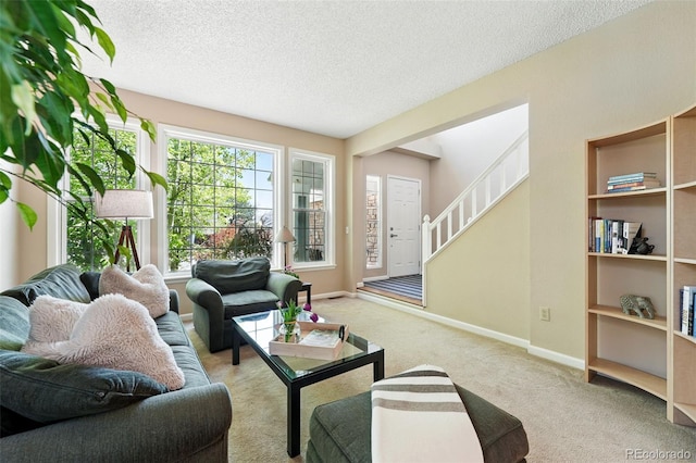 carpeted living area with a textured ceiling, stairs, and baseboards