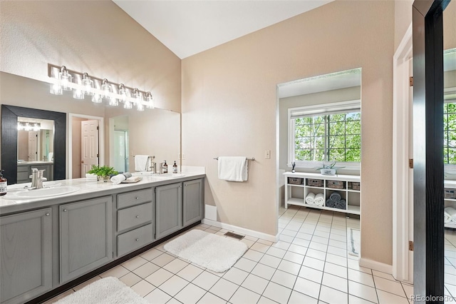bathroom with double vanity, vaulted ceiling, baseboards, and a sink