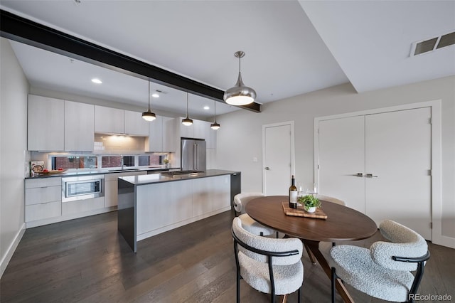 kitchen with stainless steel appliances, dark wood-style flooring, visible vents, and decorative light fixtures