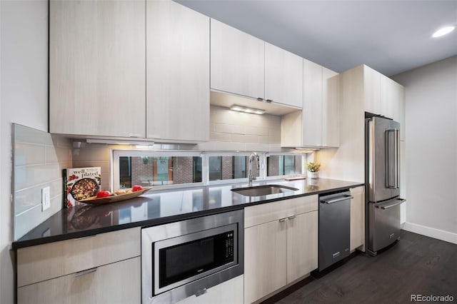 kitchen featuring baseboards, decorative backsplash, appliances with stainless steel finishes, dark wood-type flooring, and a sink