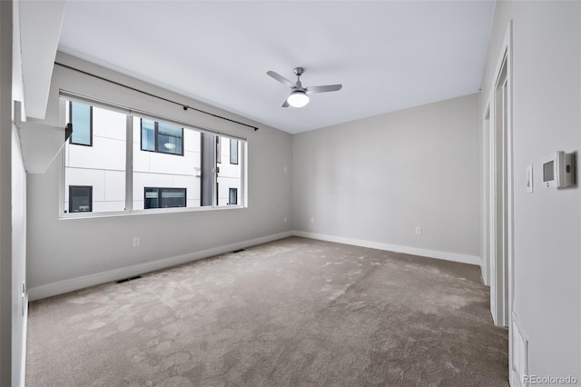 unfurnished room featuring a ceiling fan, carpet, visible vents, and baseboards