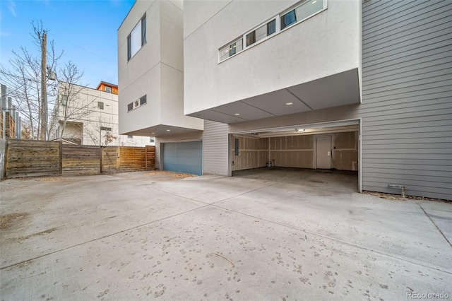 exterior space with a garage, concrete driveway, fence, and stucco siding