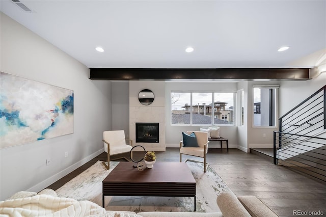 living room with a fireplace, wood finished floors, visible vents, baseboards, and stairs