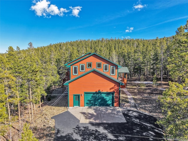 398 Mountain View Dr, Black Hawk, CO 80422 - rustic home featuring a forest view, concrete driveway, and an attached garage
