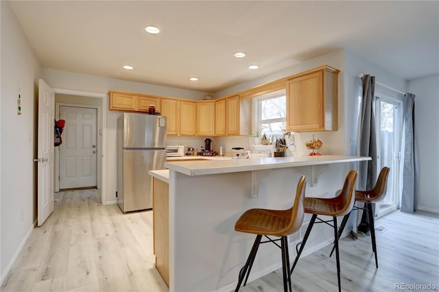 kitchen featuring light brown cabinetry, freestanding refrigerator, and a healthy amount of sunlight