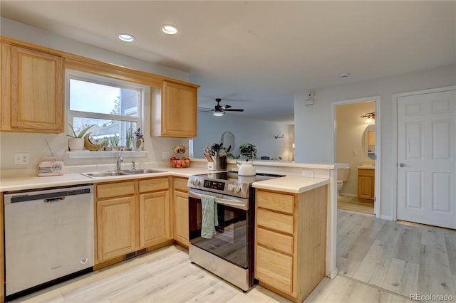 kitchen featuring light wood-style flooring, light brown cabinetry, appliances with stainless steel finishes, a sink, and a peninsula