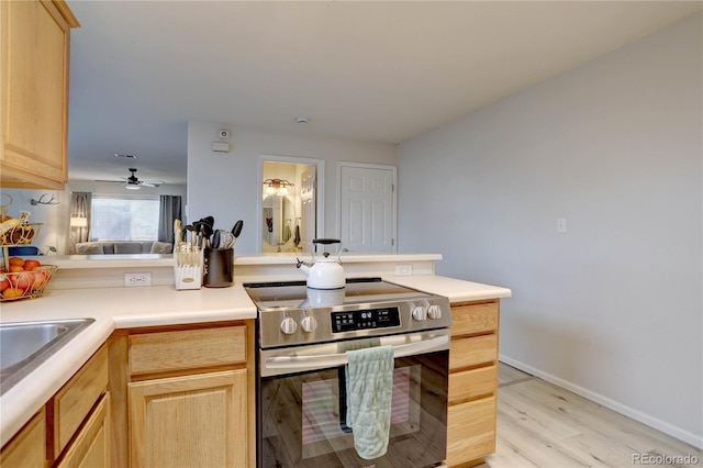 kitchen featuring light brown cabinetry, light wood finished floors, and stainless steel electric stove