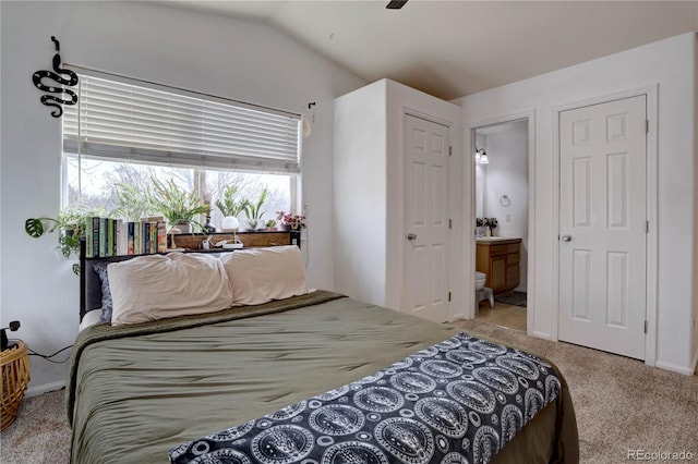 bedroom featuring vaulted ceiling, carpet, and ensuite bath