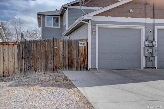 garage with concrete driveway and fence