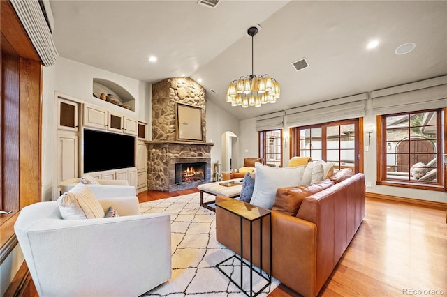 18 Club Ln, Littleton, CO 80123 - living room featuring visible vents, vaulted ceiling, an inviting chandelier, a fireplace, and light wood-style floors