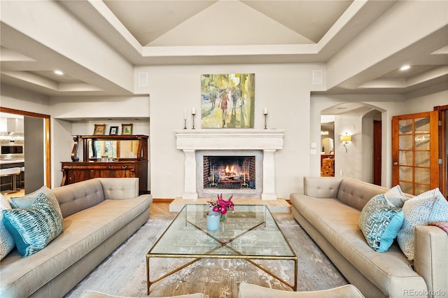 18 Club Ln, Littleton, CO 80123 - living area featuring a lit fireplace, vaulted ceiling, a raised ceiling, and arched walkways
