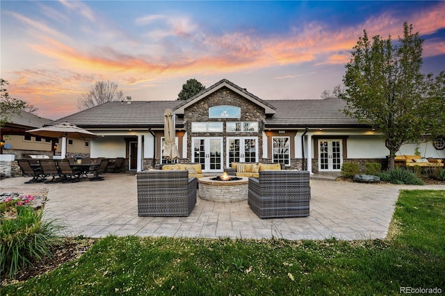 18 Club Ln, Littleton, CO 80123 - back of house at dusk featuring french doors, a patio area, stucco siding, stone siding, and an outdoor living space with a fire pit