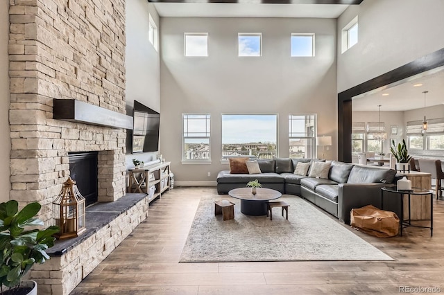 living area with wood-type flooring, baseboards, a fireplace, and a towering ceiling