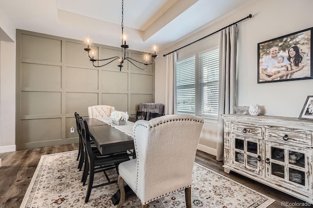 dining room featuring a decorative wall, a chandelier, baseboards, dark wood-type flooring, and a tray ceiling