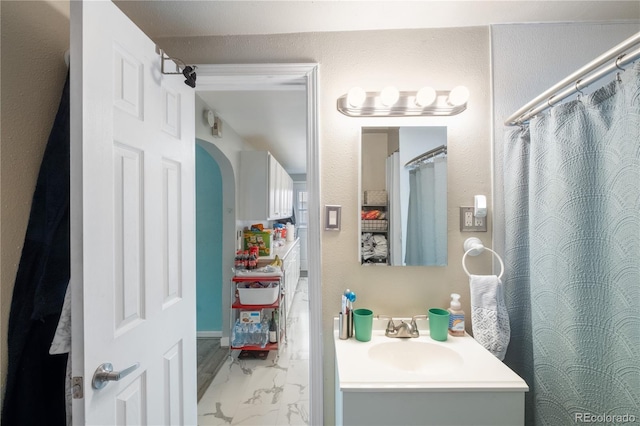 bathroom with marble finish floor, a shower with curtain, and vanity