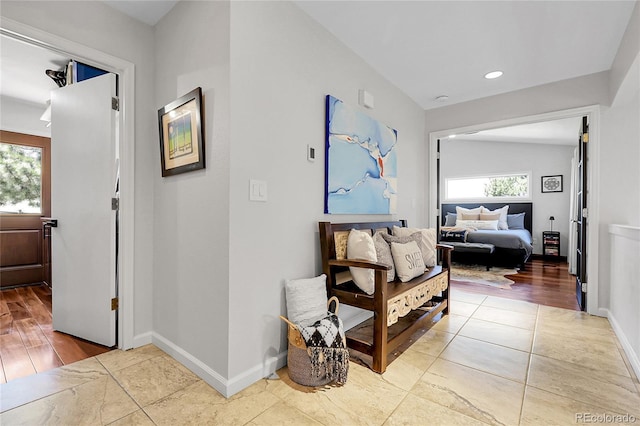 corridor with tile patterned flooring, a wealth of natural light, baseboards, and recessed lighting