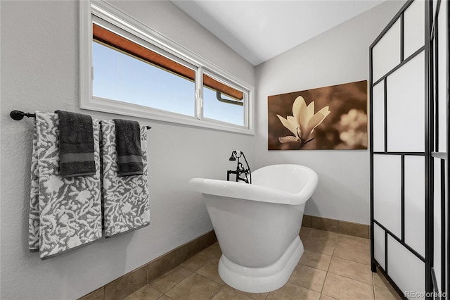 full bathroom with tile patterned floors, baseboards, and a freestanding tub