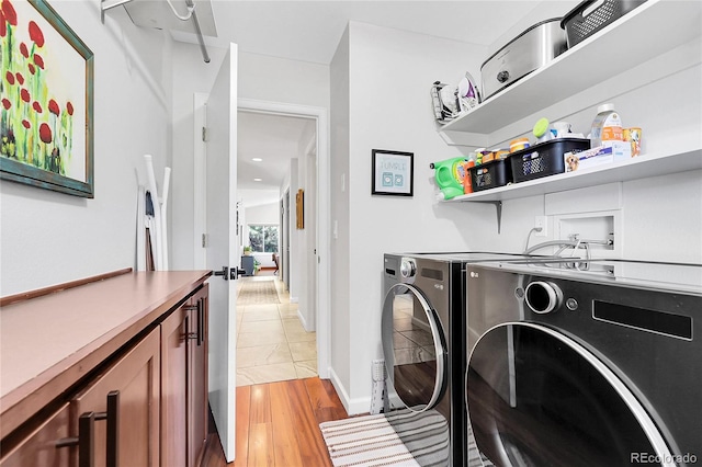 clothes washing area with washer and dryer, cabinet space, and light wood finished floors