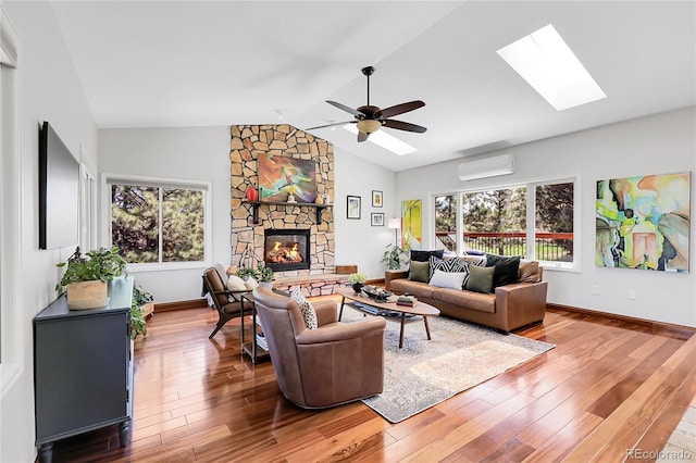 living room featuring a fireplace, a healthy amount of sunlight, wood finished floors, and an AC wall unit