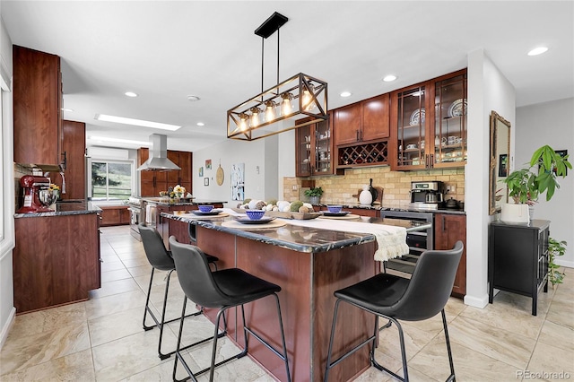 kitchen with recessed lighting, glass insert cabinets, a breakfast bar, wall chimney exhaust hood, and tasteful backsplash