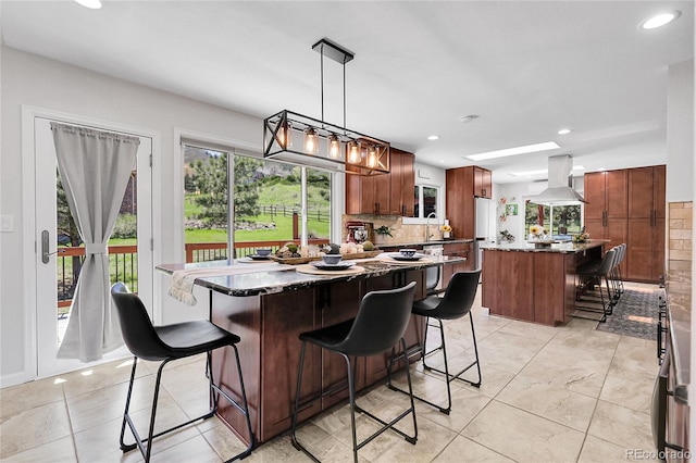 kitchen with a sink, island exhaust hood, recessed lighting, backsplash, and a kitchen island