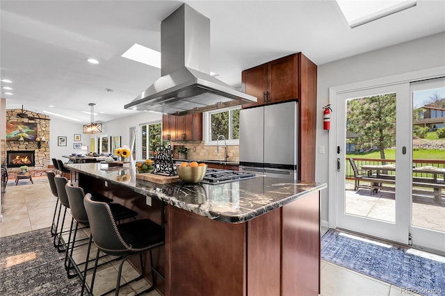 kitchen featuring island exhaust hood, dark stone countertops, stainless steel appliances, tasteful backsplash, and recessed lighting