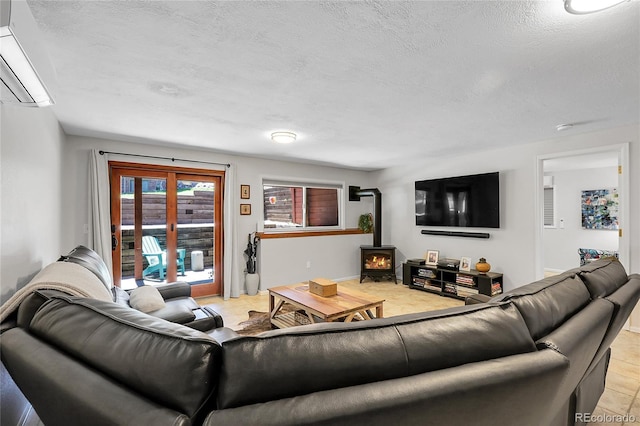living room with baseboards, a wood stove, a wall unit AC, and a textured ceiling