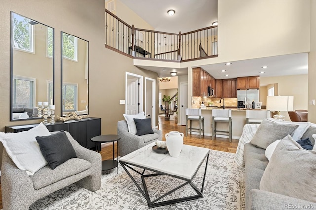 living room featuring a high ceiling, light wood-style flooring, and visible vents