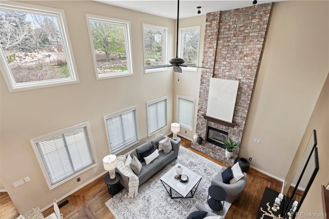 living room featuring a ceiling fan, baseboards, wood finished floors, and a fireplace