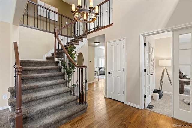 stairway with baseboards, wood finished floors, and a notable chandelier