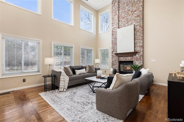 living area featuring baseboards, a high ceiling, a healthy amount of sunlight, and a fireplace
